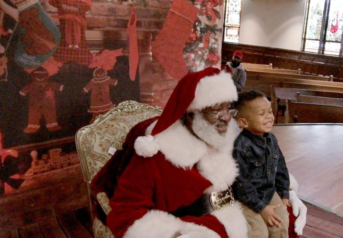 Elijah Rodgers sits and smiles with Santa Claus at the Hayti Heritage Center in Durham, NC, on Friday, Dec. 22, 2017.