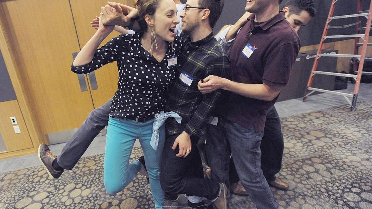 RTI International staff members Nichole Smith, Michael Duprey and Ethan Ritchie, from left, participate in a team building task, standing in a small roped area, to earn parts to assemble into a total of 10 bicycles for families from Big Brothers and Big Sisters of the Triangle.