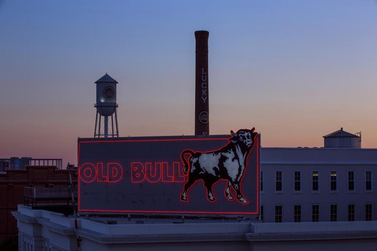 The sun sets behind iconic symbols of the downtown Durham skyline.
