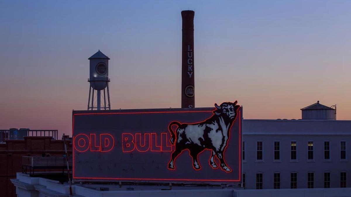 The sun sets behind iconic symbols of the downtown Durham skyline.