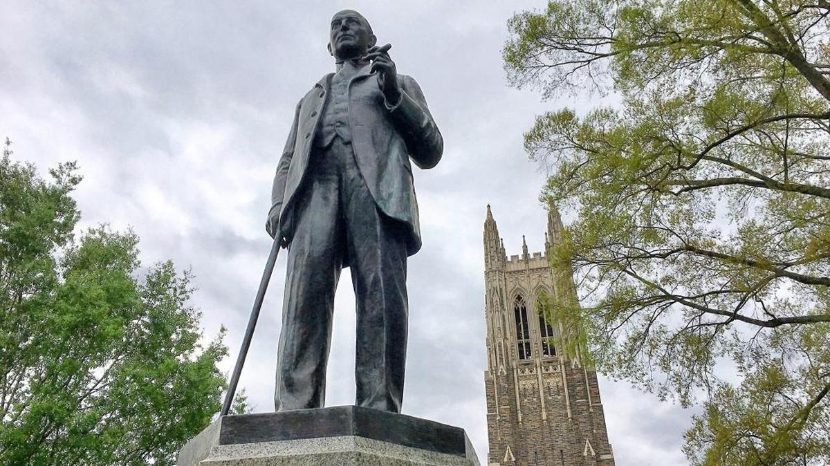 A statue of James Buchanan (Buck) Duke greets visitors to West Campus at Duke University. Duke Chapel is pictured at rear.