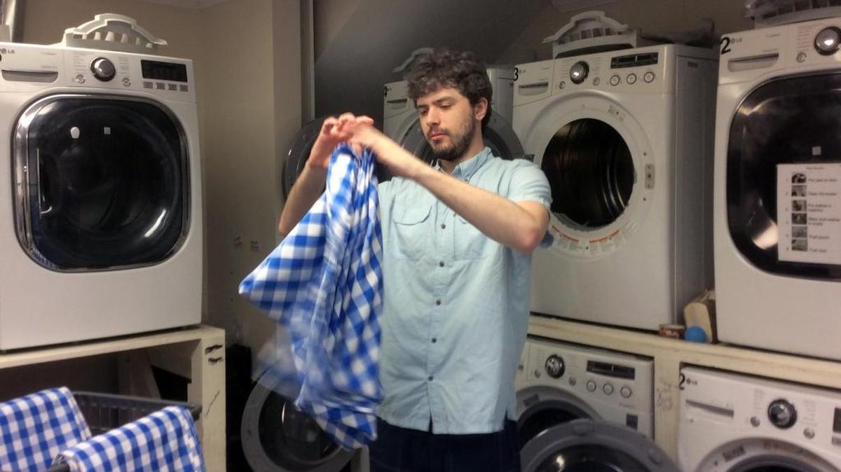 Patrick Eden straightens up between loads at EV Laundry in the Extraordinary Ventures facility on South Elliott Road in Chapel Hill. Eden, 25, has autism and has worked at EV Laundry for more than four years. He now manages fellow employees.