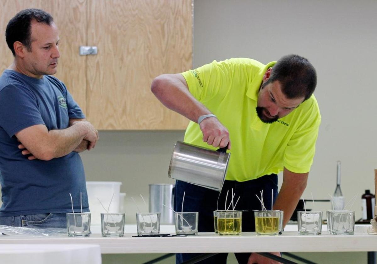 Job coach Eric Mazochi, left, watches as employee Bryan Norwood pours hot wax into a candle mold in October 2012 at Extraordinary Ventures in Chapel Hill.