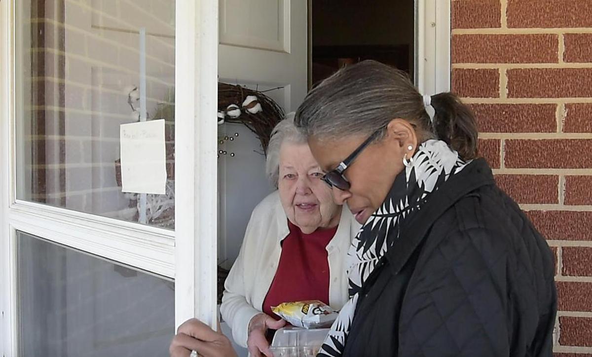 Volunteer Veamarea Burton, at right, delivers a hotdog meal to resident Mary Pixley on Monday, March 26, 2018, in Cedar Grove. The Orange County Sheriff's Office prepares hotdogs with slaw and baked beans once a month. The meals then are delivered by volunteers with the Orange County Rural Alliance. Burton also is an interim chaplain at UNC Hospitals in Hillsborough.