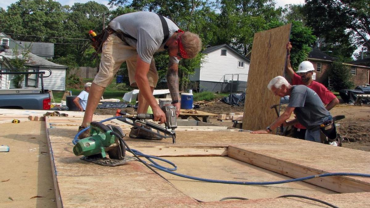 At left, site supervisor Matthew Henrickson nails boards to a wall frame while his Habitat for Humanity of Orange County work crew waits to lay down another panel for a home at 605 Craig St. in Chapel Hill.