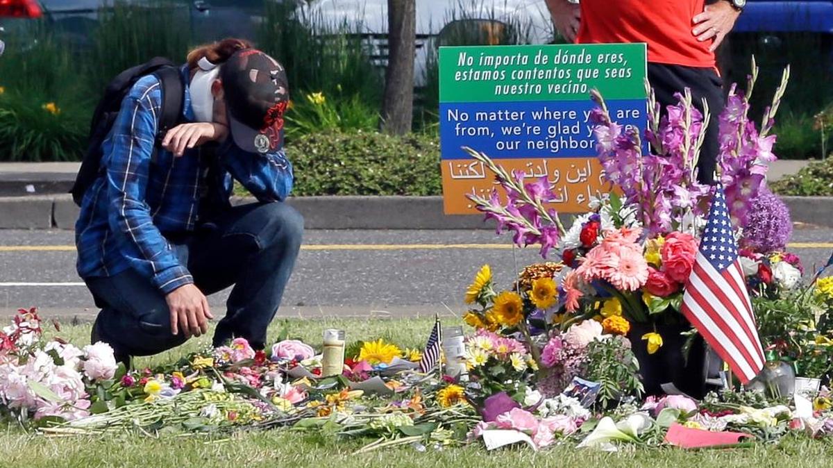 An unidentified man kneels in Portland, Ore., on May 31 at a memorial for two men fatally stabbed on a light rail train in Portland last week. The men were killed and a third injured as they tried to shield young women from an anti-Muslim tirade.