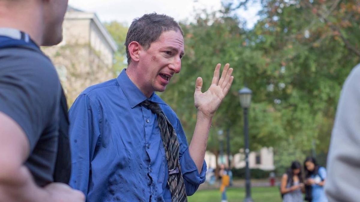UNC professor Dan Reichart tries to extinguish a fire allegedly set by a man who was later arrested when a device explodes at the base of the Davie Poplar on the UNC campus Thursday afternoon, Nov. 2, 2017. Reichart is being treated for burns, and the suspect is in custody and being evaluated.