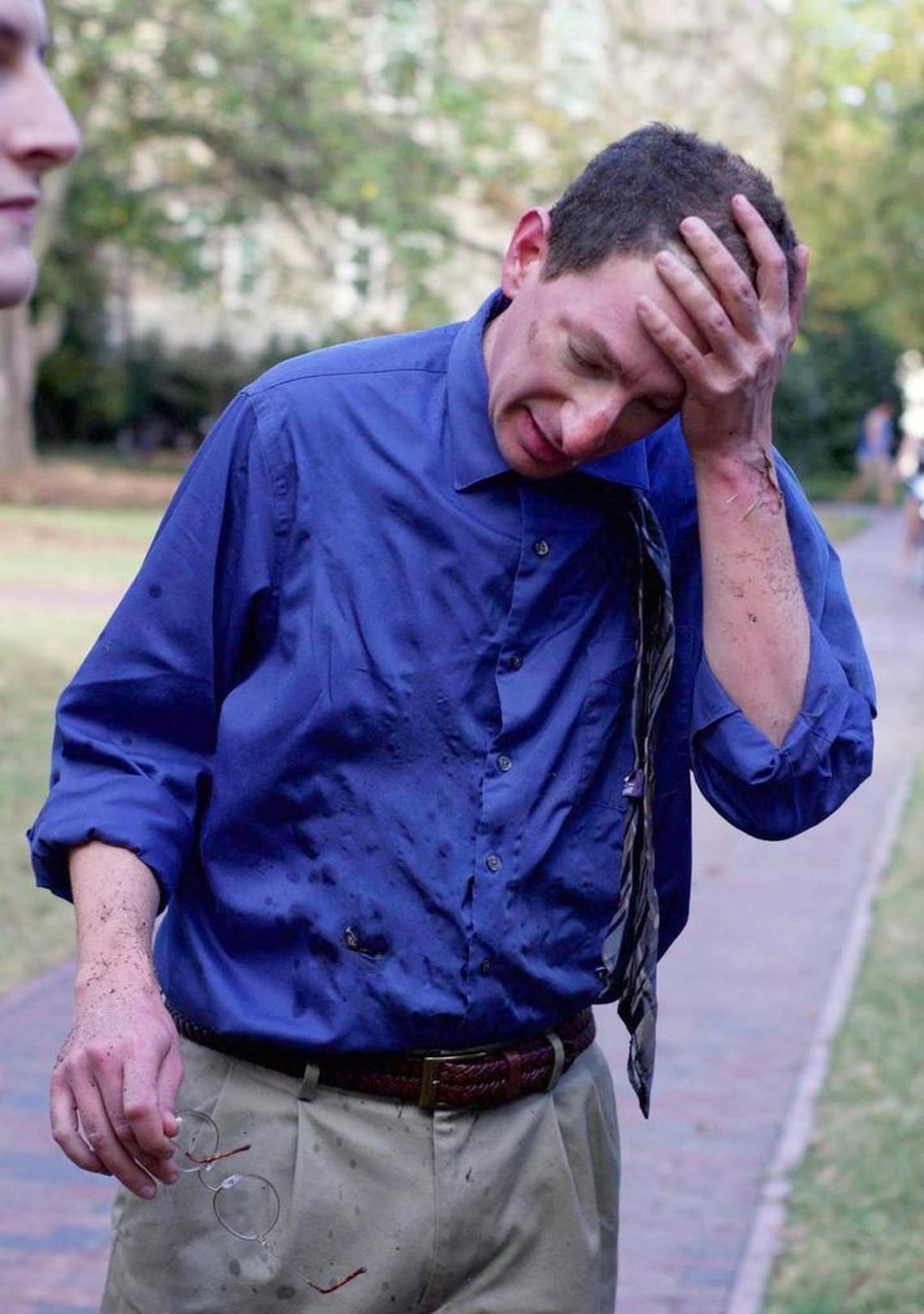A man identified as UNC professor Dan Reichart wipes his forehead as he recovers from an explosion at the base of the Davie Poplar on the campus of UNC. Reichart was trying to extinguish a fire allegedly set by another man at the tree when there was an explosion Thursday afternoon, Nov. 2, 2017. A suspect was arrested a short time after the explosion.