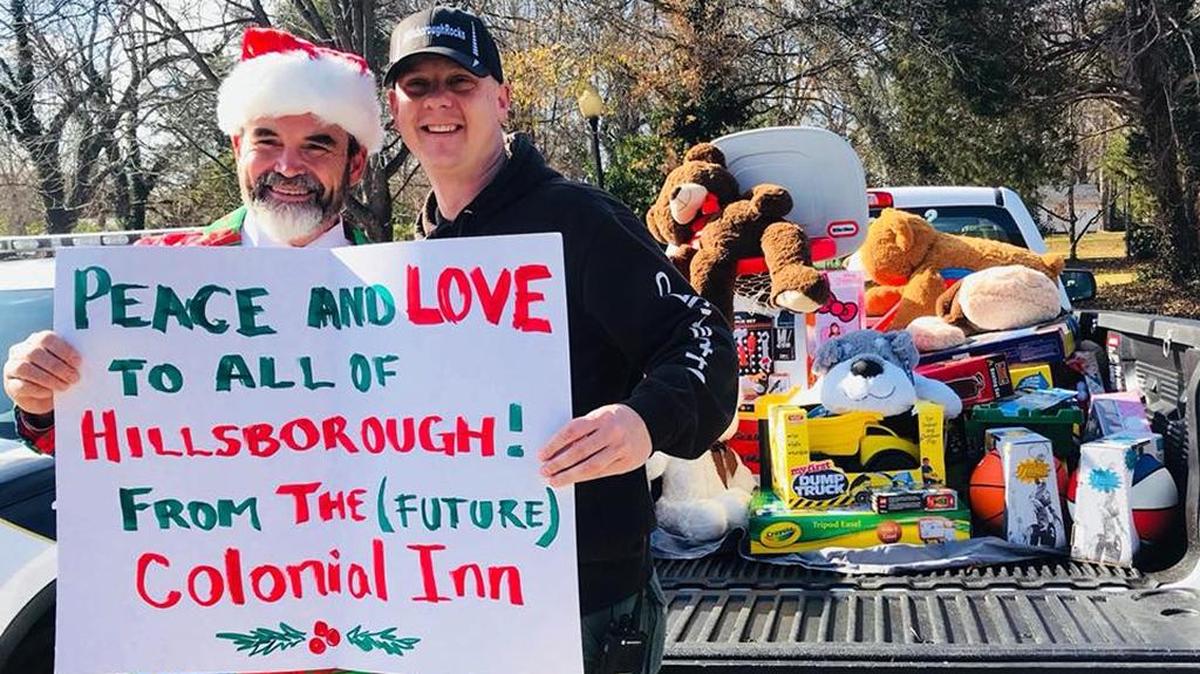 Attorney Sam Coleman, at left, poses with a Hillsborough Police officer and a sign hinting at the future of the Colonial Inn after dropping off a truckload of Christmas toys ahead of Santa’s visit to the Police Department on Dec. 14. Coleman is an attorney with the firm of Coleman, Gledhill, Hargrave, Merritt and Rainsford.