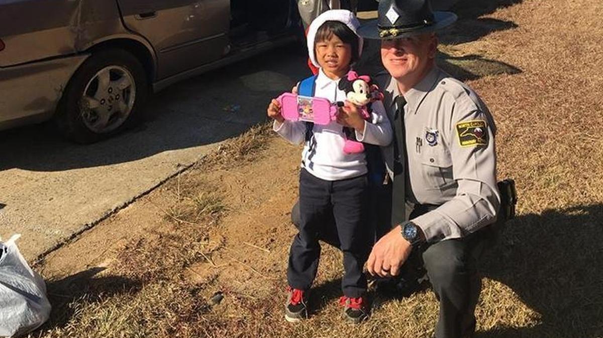 N.C. Highway Patrol Trooper Michael Dodson poses for a picture with Mary, 5, after her family wrecked their car on Interstate 40 near Hillsborough on Thursday, Nov. 30, 2017.