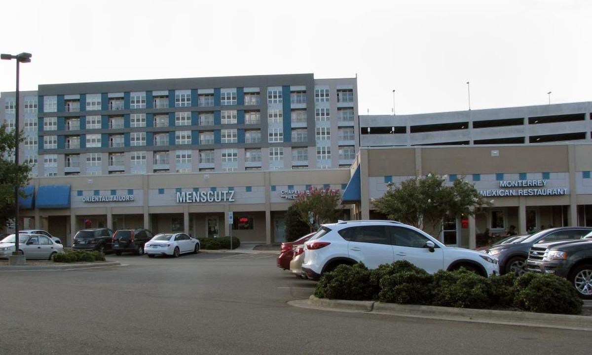 Multiple floors of the seven-story Berkshire Chapel Hill and its parking deck rise behind the one-story Elliott Square shops on South Elliott Road. The Berkshire continues to be a target of criticism for its size and height, which is an anomaly in the new Blue Hill (Ephesus Fordham) district.