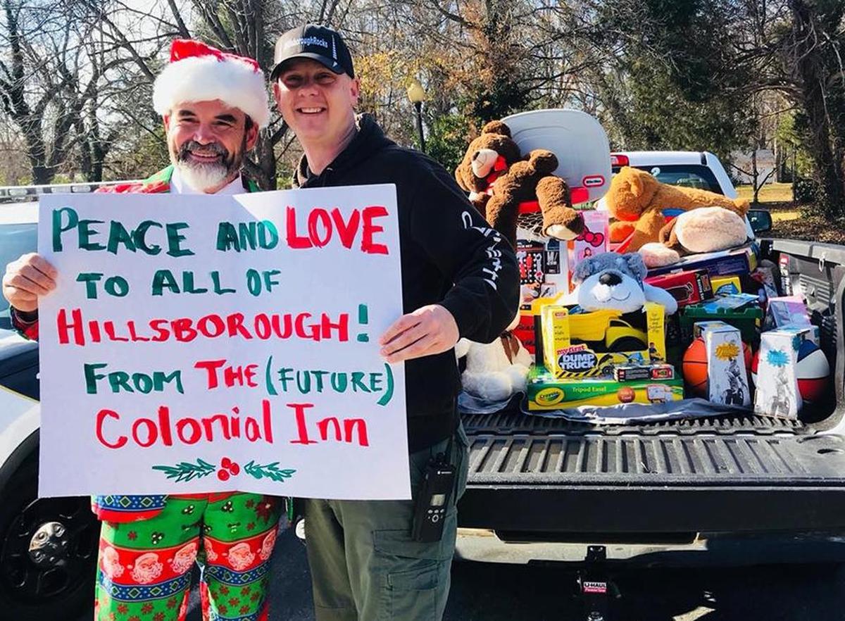 Attorney Sam Coleman, at left, poses with a Hillsborough Police officer and a sign hinting at the future of the Colonial Inn after dropping off a truckload of Christmas toys ahead of Santa’s visit to the Police Department on Dec. 14. Coleman is an attorney with the firm of Coleman, Gledhill, Hargrave, Merritt and Rainsford.