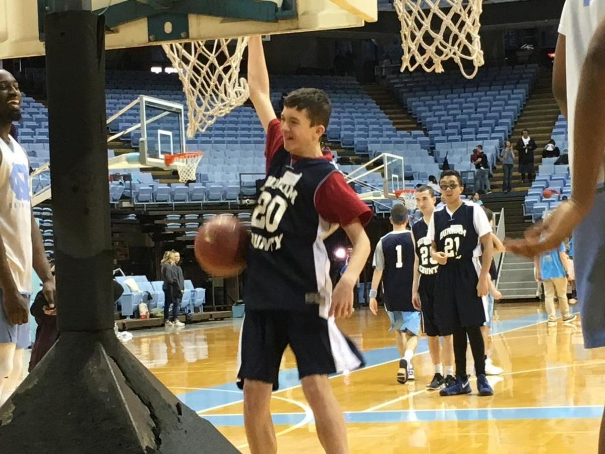 Voyager Academy’s Jacob Ross slams a basketball through a hoop as UNC star Theo Pinson watches during the 15th annual clinic for Special Olympics North Carolina athletes hosted by the UNC men’s basketball.