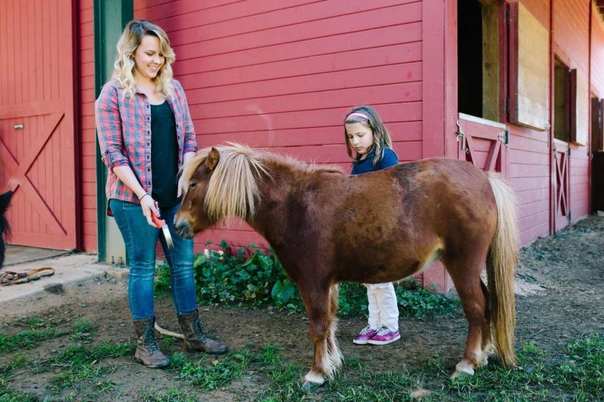 Therapist Katherine Harrell Jones and Patience, a student at the Crossnore School & Children’s Home, work with Rockstar, a therapy miniature horse, in Avery County, NC.