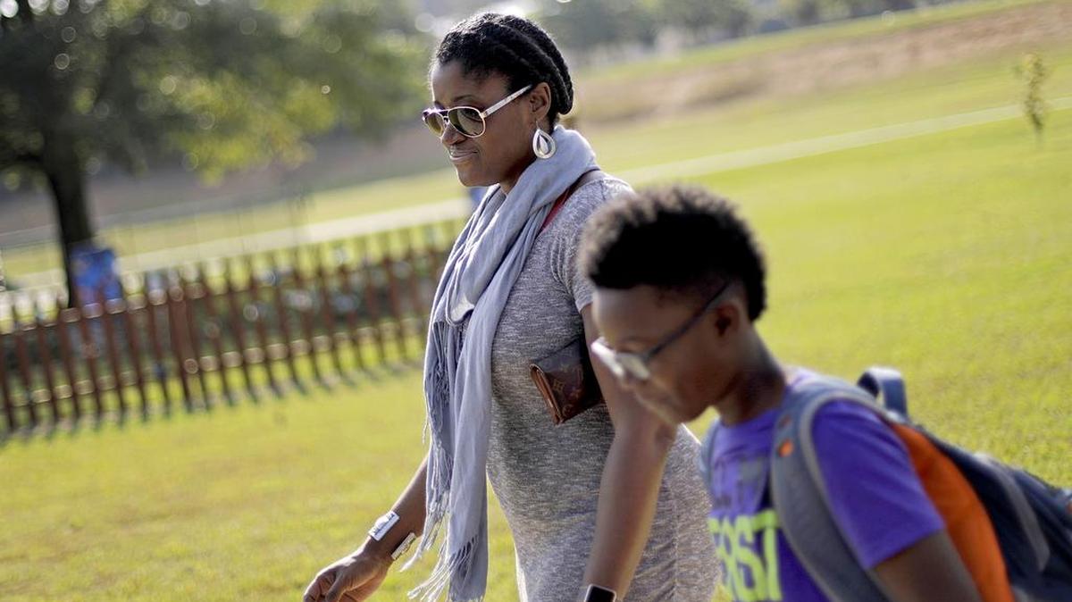 Corrie Davis, left, picks up her son Turner from Big Shanty Elementary School in Kennesaw, Ga. A new battle line has formed in the national debate over Civil War flags and symbols. The school last month invited fifth-graders to dress up as characters from the Civil War. Davis says a white student dressed as a plantation owner approached her son and said “You are my slave.” Davis says she wants Cobb County school officials to understand the pain that caused her son. She also wants the school to stop the annual Civil War dress-up day.