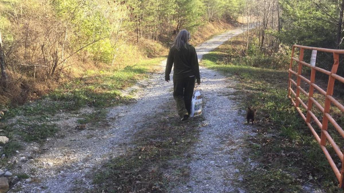 In this Nov. 21, 2017 photo, Tommie Burchfield walks down the gravel drive toward her home in rural McCreary County, Ky., after getting books from the bookmobile.