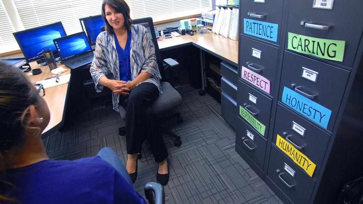 Bloomington Public Schools school psychologist Mary Ann Whalen talks about suicide prevention with an Illinois State University intern in her office in Normal, Ill. Whalen said teachers are trained to follow a crisis response plan if an at-risk student is identified. Signs posted on her file cabinets underline basic human qualities that when shared, can lead to healthy outcomes in any almost any situation.