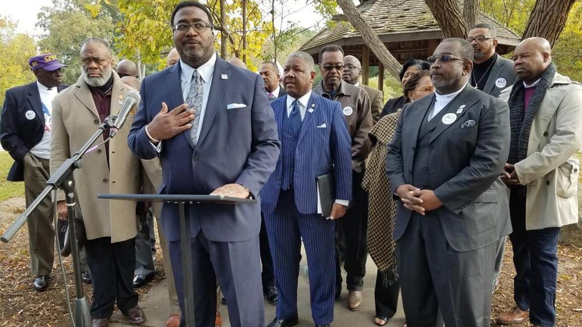 About a dozen African-American Durham clergy members show their support for mayoral candidate Farad Ali (at lectern) at a news conference at Forest Hills Park Wednesday.