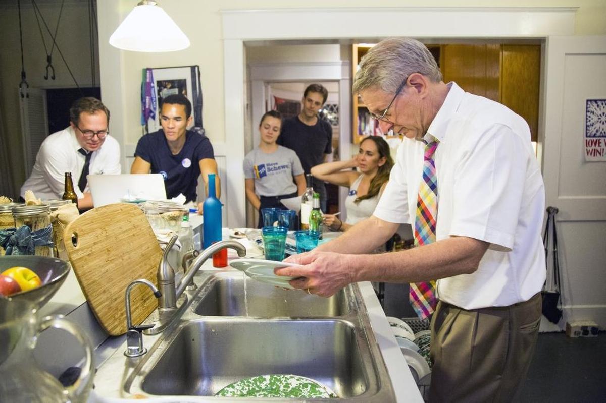 Durham mayoral candidate Steve Schewel washes dishes in his kitchen while his campaign staff watches the results of the mayoral primary election on Tuesday, Oct. 10, 2017, in Durham, NC. Schewel held a strong lead throughout the evening, finishing with 51.2 percent of the vote.