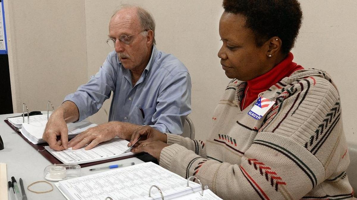 Tom Clark, assistant judge, and Kem (cq) Gilmore work as a team to get forms to voters the old fashioned way at E.K. Powe Elementary School voting precinct in Durham on Nov. 8, 2016. A computer glitch shut down the county's new electronic voting system causing some delays at some precincts.