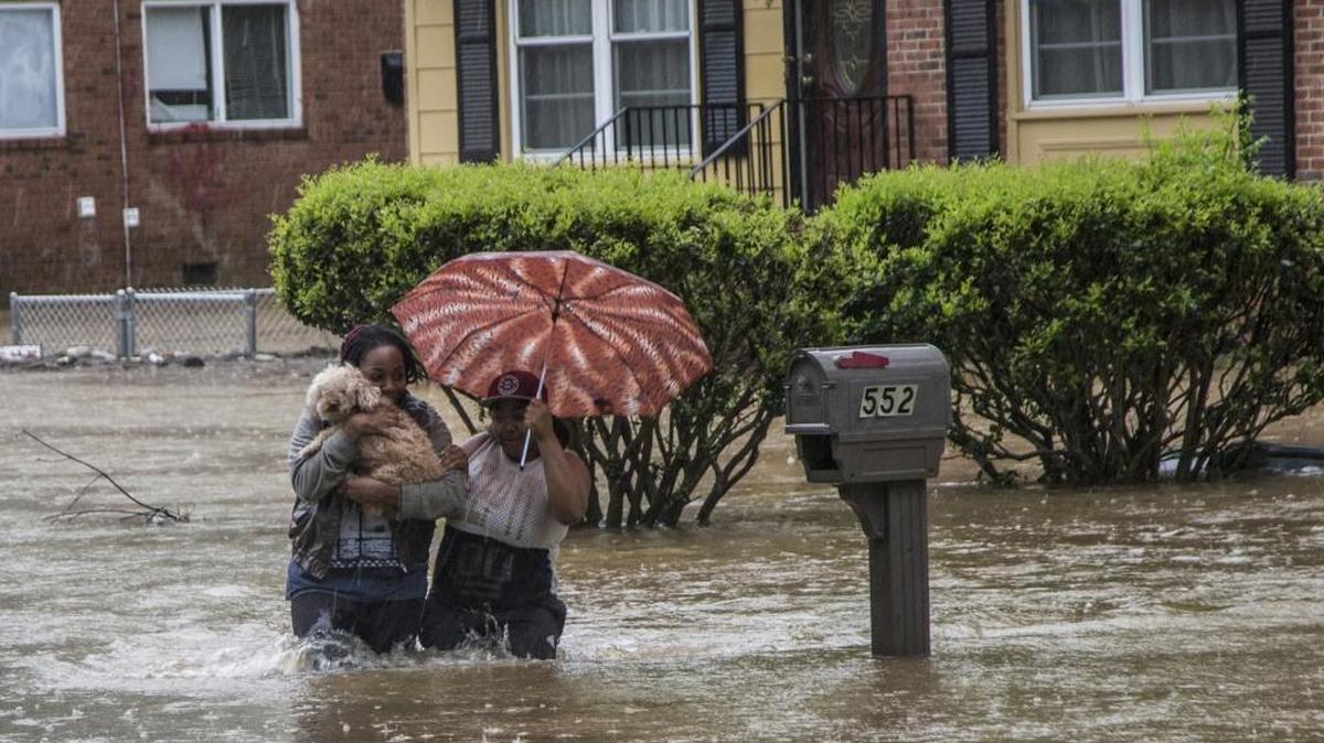 Nautica Jackson, left, and Aniya Ruffin walk through floodwaters with their dog as water threatened to enter their home in Raleigh on Tuesday.