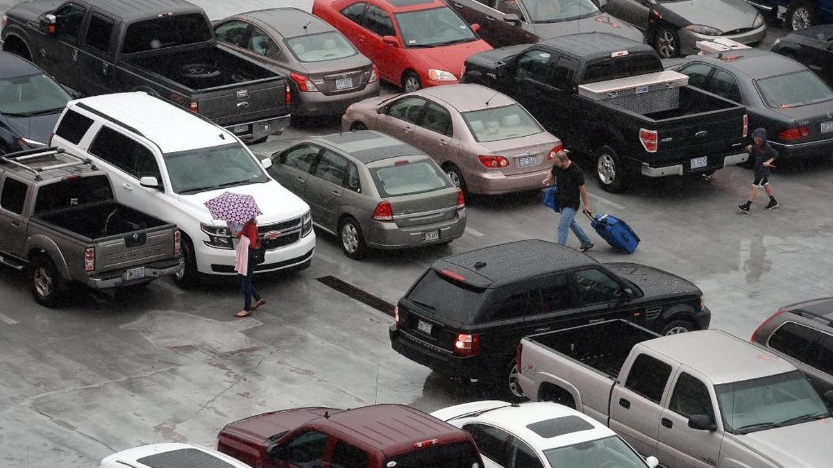 Travelers head to their cars from Terminal 2 in a driving rain storm at Raleigh-Durham International Airport in this file photo from December 2015. The airport is installing new equipment at the entrance and exits of its parking decks to accommodate a new online booking system that will be available early next year.