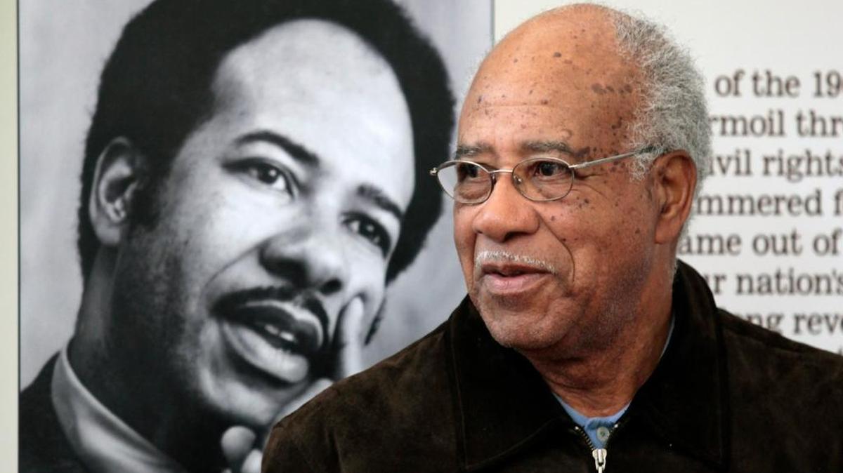 Former Chapel Hill, NC Mayor Howard Lee stands next to a 1970s photo of himself at the Chapel Hill Library, Friday, November 21, 2014.