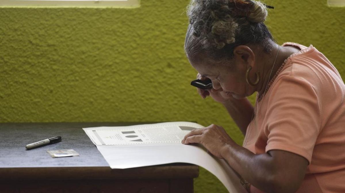 Puerto Rican resident Marla Quinones looks carefully at her ballot with a magnifying glass before voting during the fifth referendum on the island's status, in San Juan, Puerto Rico, Sunday, Jun. 11, 2017.