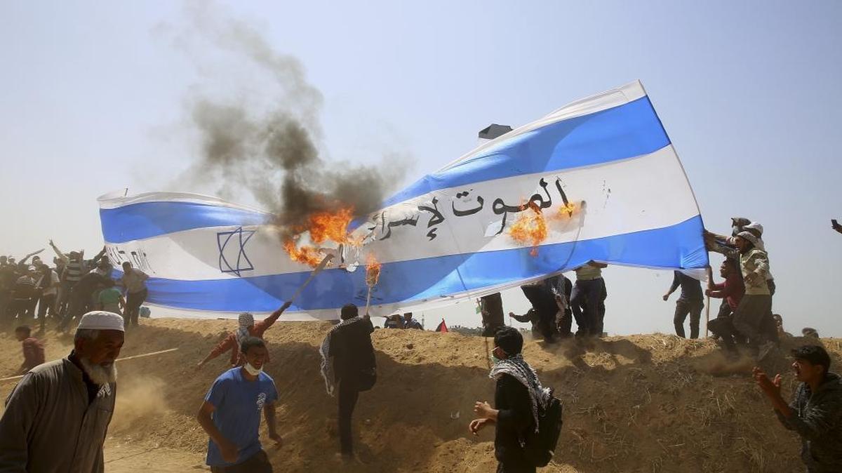 Palestinian protesters burn a representation of an Israeli flag during clashes with Israeli troops along Gaza's border with Israel, Friday, April 6, 2018.