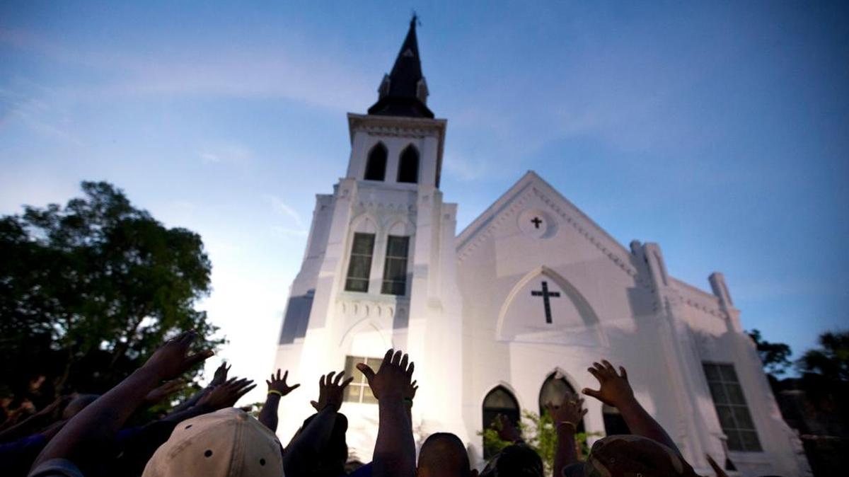 In this June 19, 2015 file photo, the men of Omega Psi Phi Fraternity Inc. lead a crowd of people in prayer outside the Emanuel AME Church, after a memorial for the nine people killed by Dylann Roof in Charleston, S.C.