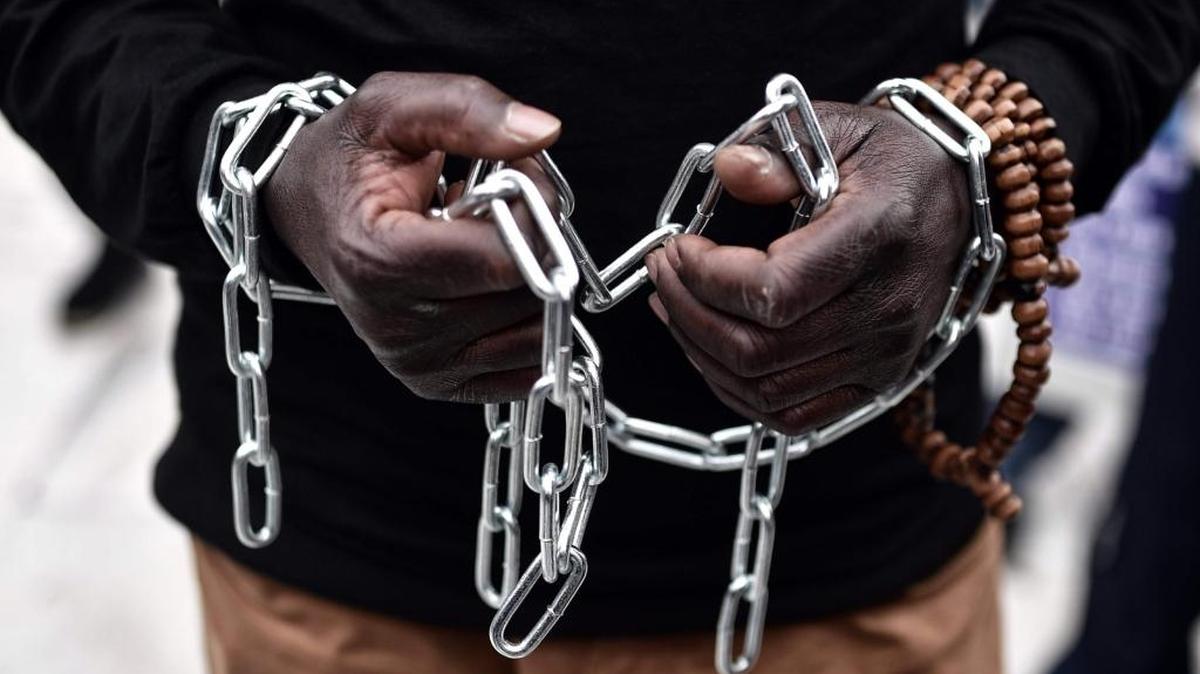 An African migrant with his hands chained, takes part in a march toward the offices of the European Union during a demonstration on Dec. 2, 2017 in central Athens, protesting against the slavery of migrants in Libya and against the deals between the European Union (EU) and Turkey and between EU and Libya.