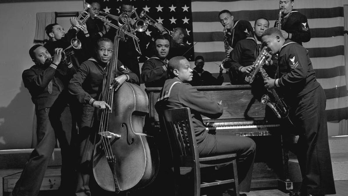 Members of the B-1 Band — an African-American Navy Band assigned to Chapel Hill during World War II — play in front of a large American flag in this North Carolina Collection archive photo.