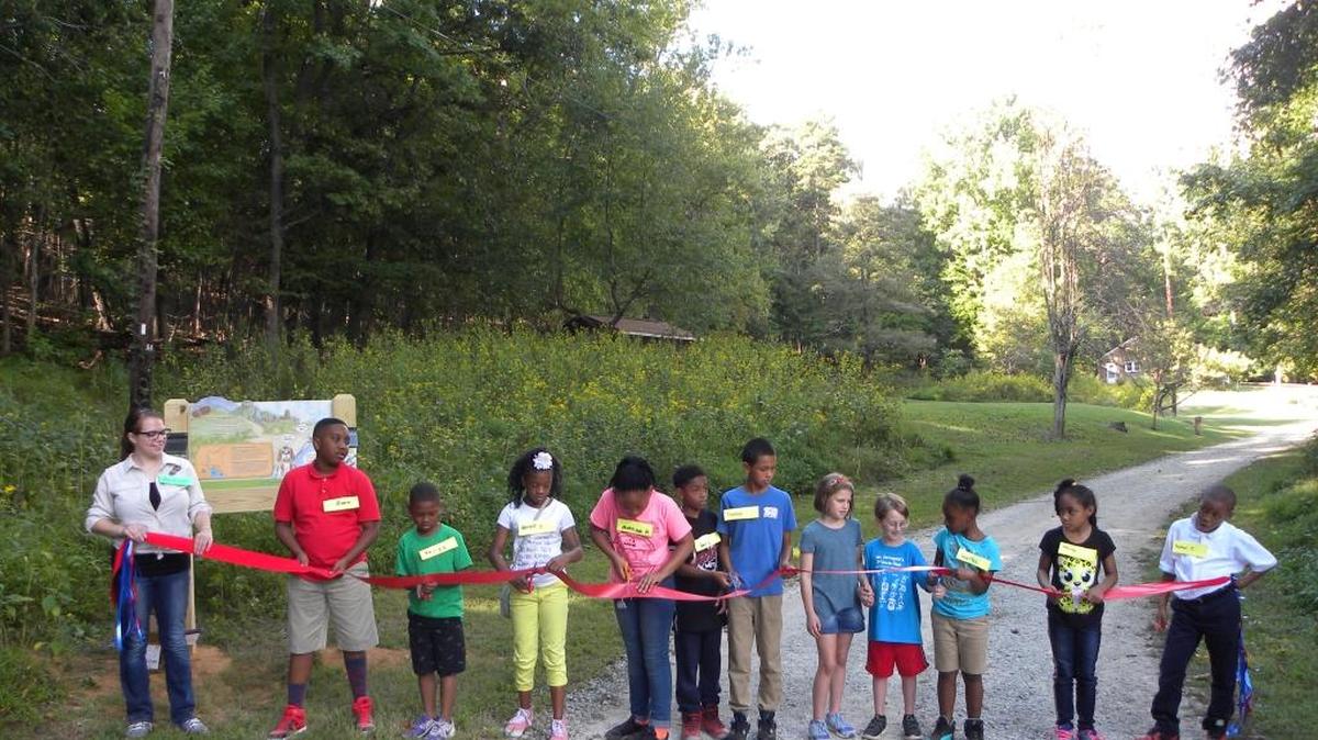Children from The Boys and Girls Club of Durham and Orange County cut a red ribbon to officially open the new Kids in Parks trail at Occoneechee Mountain in Hillsborough.
