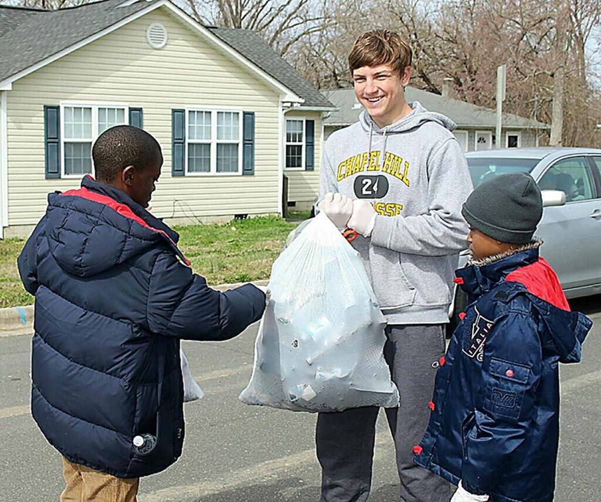 A SKJAJA volunteer helps clean up litter with neighborhood children.