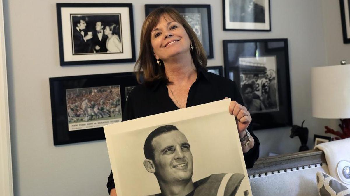 In this July 26, 2017 photo, Lise Hudson poses with photos of her husband, Jim Hudson, who played football for the University of Texas and the New York Jets in the 1960's, at her home in Austin, Texas. After his death, researchers found that Hudson suffered from stage IV chronic traumatic encephalopathy, the highest level of the brain disease.