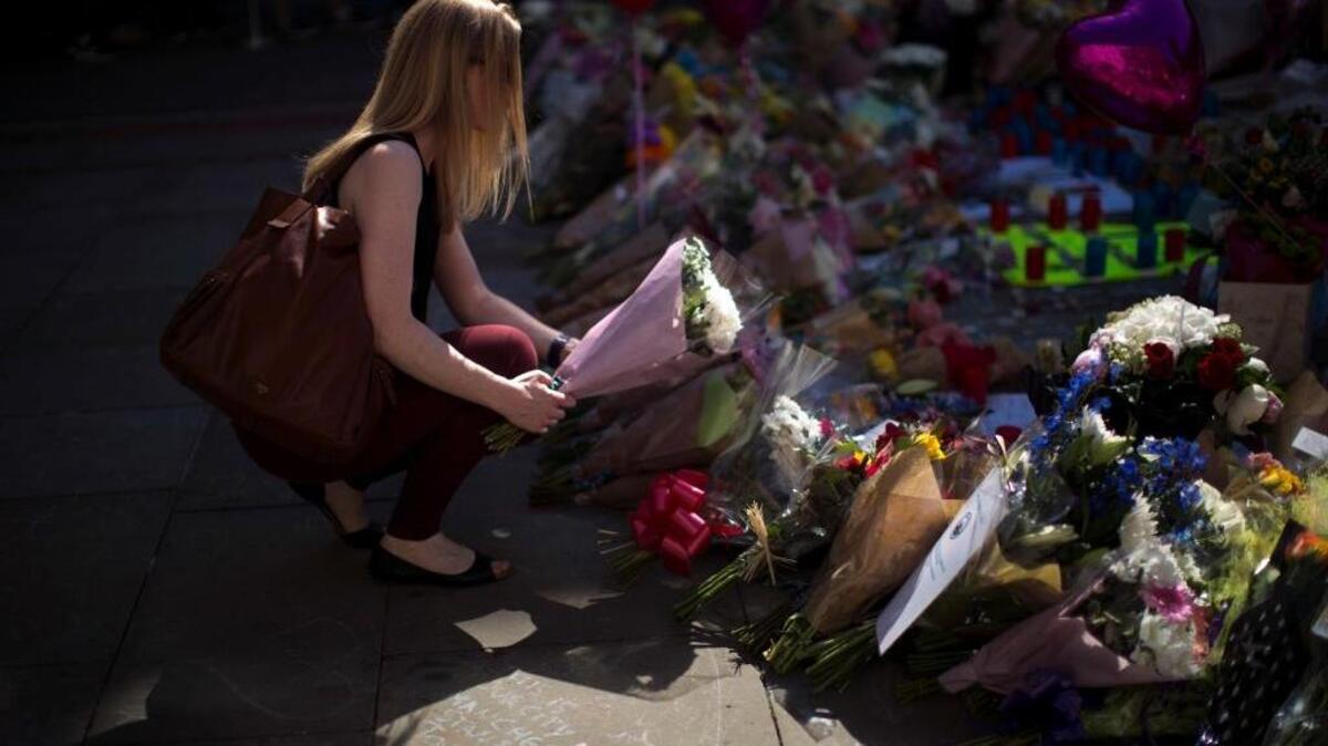 A woman places flowers for the victims of the May 21 bombing at St Ann's Square in central Manchester, England, Friday, May 26, 2017.