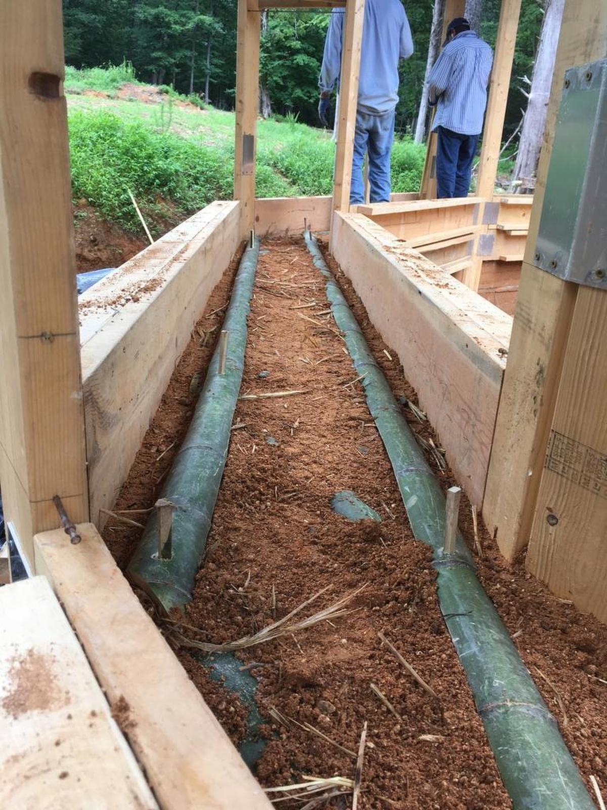 Pipes will carry water heated from a compost pile to help warm the Ecoheal Center outside Chapel Hill during cold weather.The walls were built in a patented formation system using natural materials.