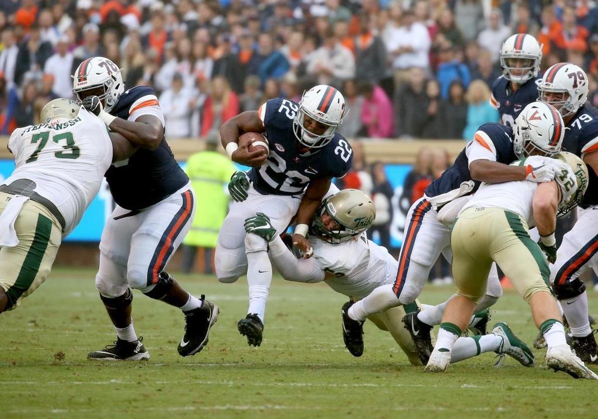 Virginia’s Daniel Hamm, middle, runs with a ball while William and Mary’s Matt Ahola tries to tackle him on Saturday.