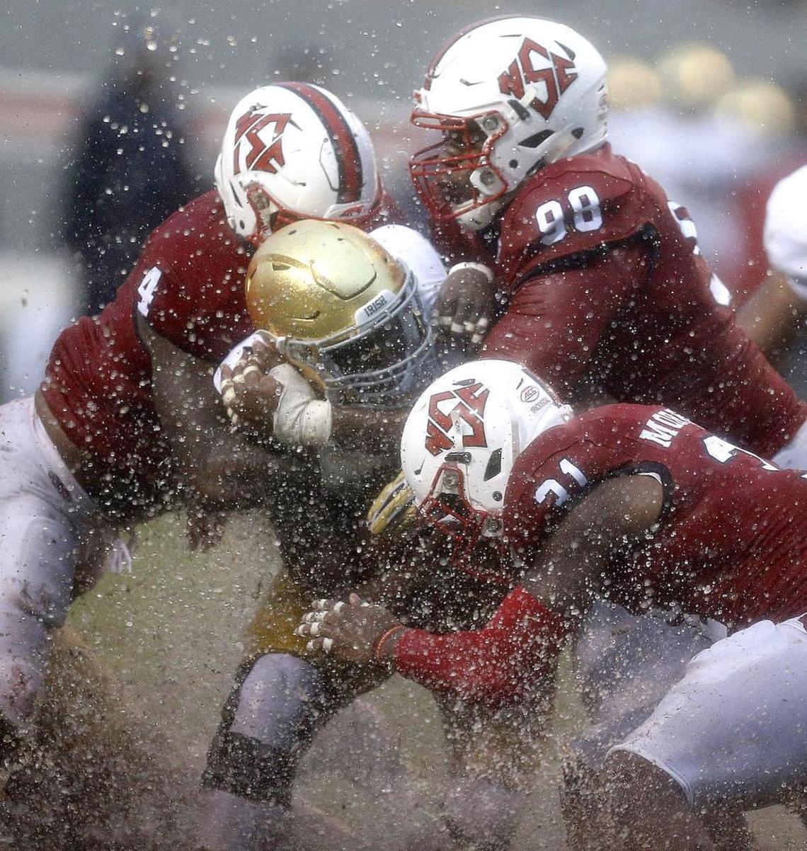 N.C. State’s Jerod Fernandez (4), B.J. Hill (98) and Jarius Morehead (31) tackle Notre Dame running back Josh Adams in a 10-3 rain-soaked win for the Wolfpack on Oct. 8.