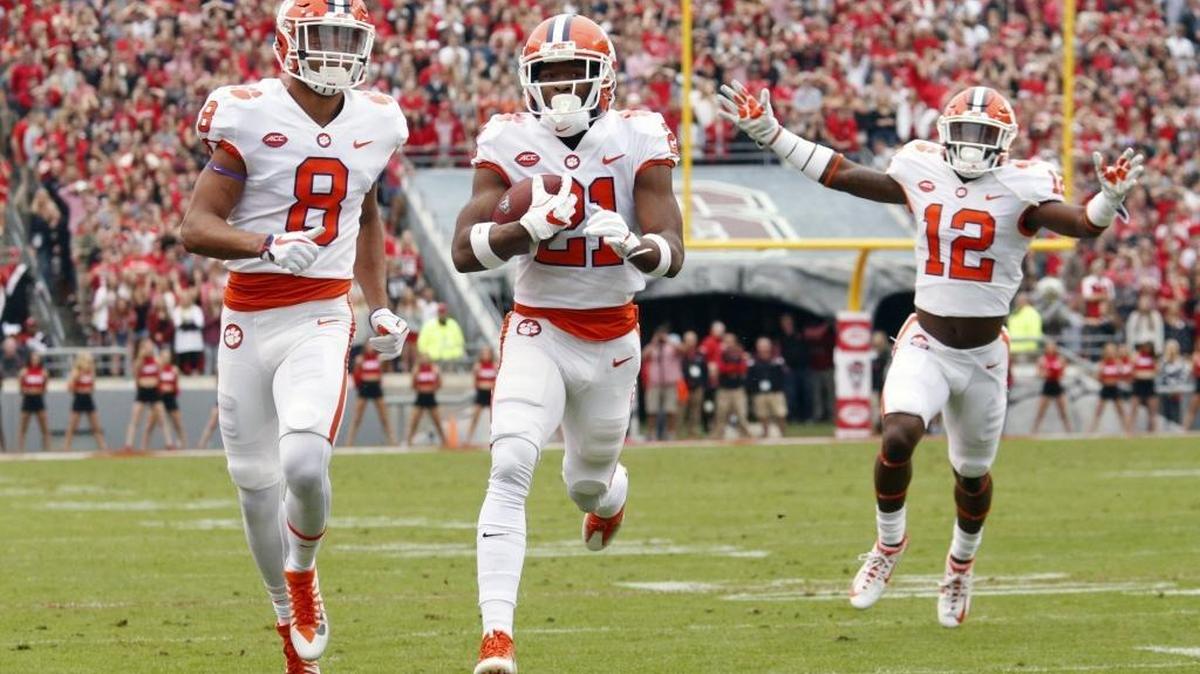 Clemson's Ray-Ray McCloud (21) runs a punt back 77 yards for a touchdown during the first quarter of an ACC college football game between the N.C. State Wolfpack and the Clemson Tigers played at Carter-Finley Stadium in Raleigh, NC on Nov. 4, 2017. Deon Cain (8) and K'VonWallace (12) escort him in.