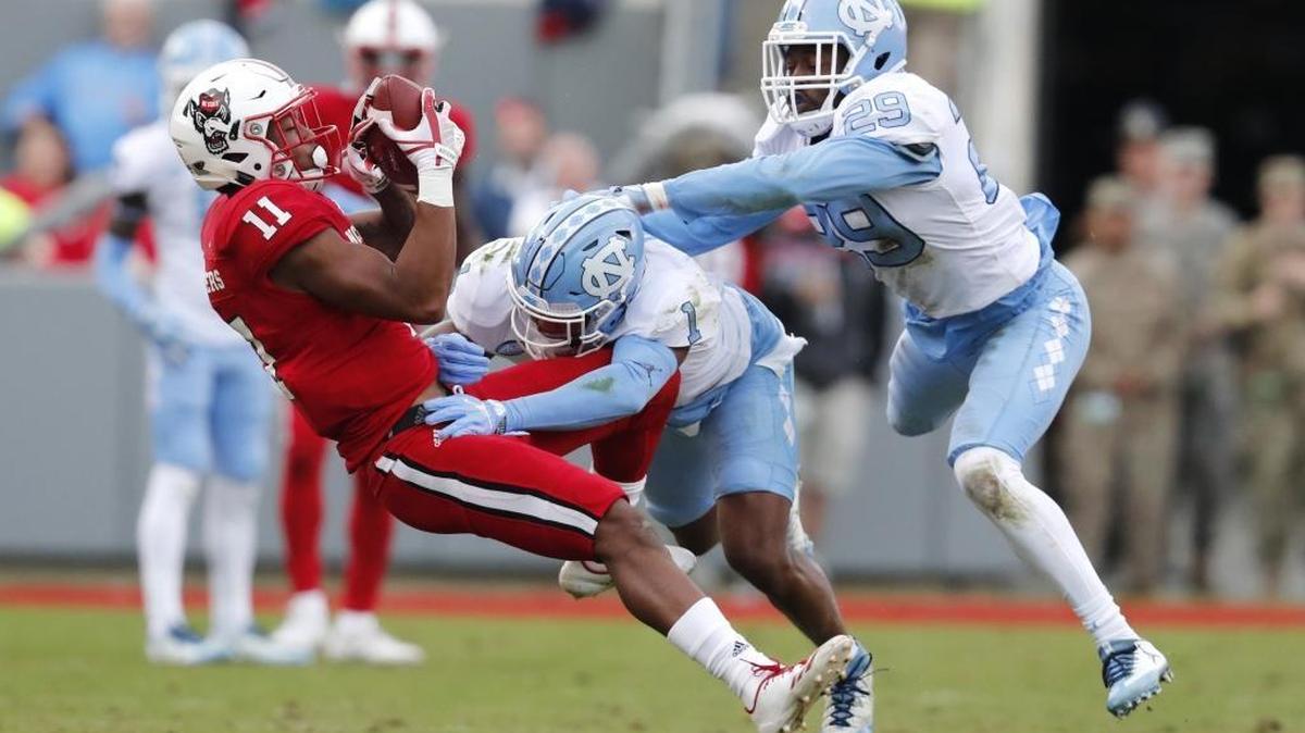 N.C. State wide receiver Jakobi Meyers (11) pulls in a reception as North Carolina safety Myles Dorn (1) and safety J.K. Britt (29) defend during the first half of N.C. State's game against UNC at Carter-Finley Stadium in Raleigh, N.C., Saturday, Nov. 25, 2017.