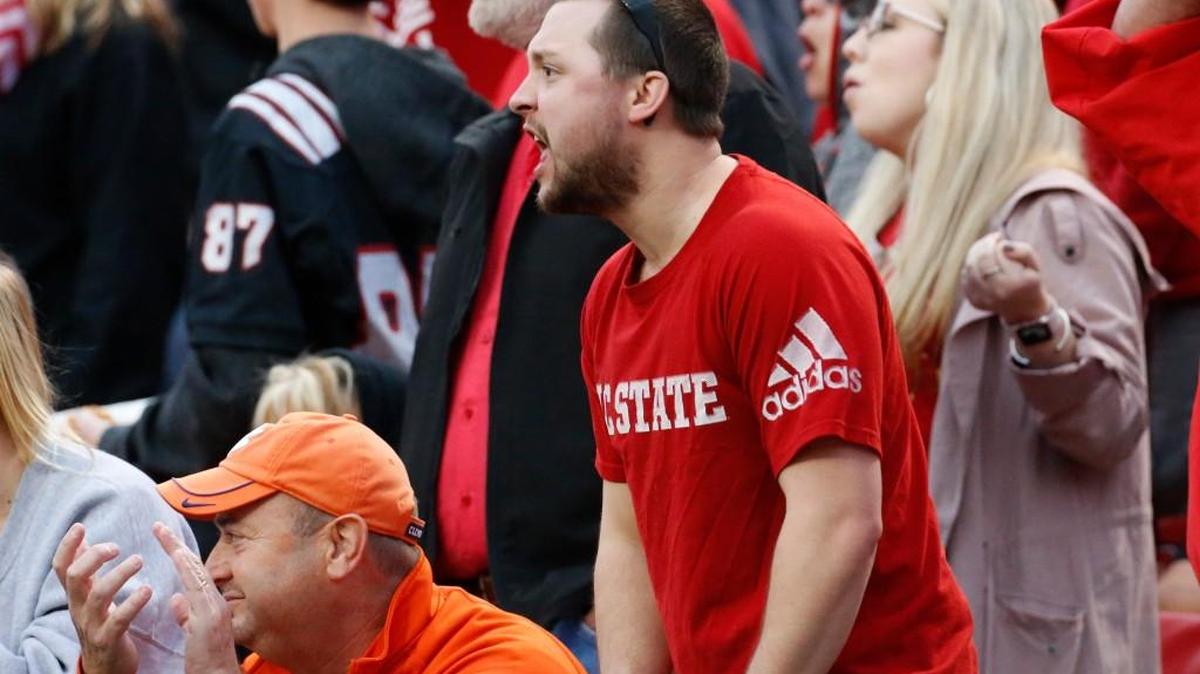 An N.C. State fan, right, disagrees with a call while a Clemson fan applauds it, left, during the third quarter.
