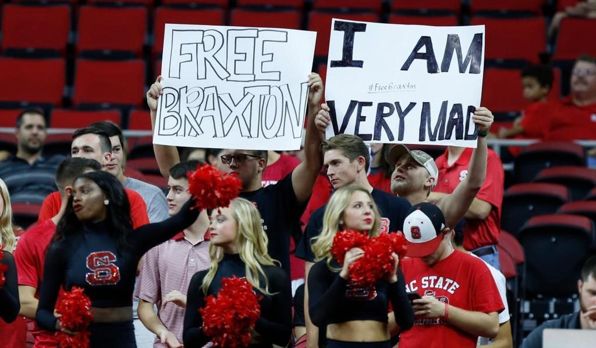 Fans hold up signs supporting Braxton Beverly during N.C. State's exhibition game against Mars Hill University at PNC Arena Friday, Nov. 3, 2017.