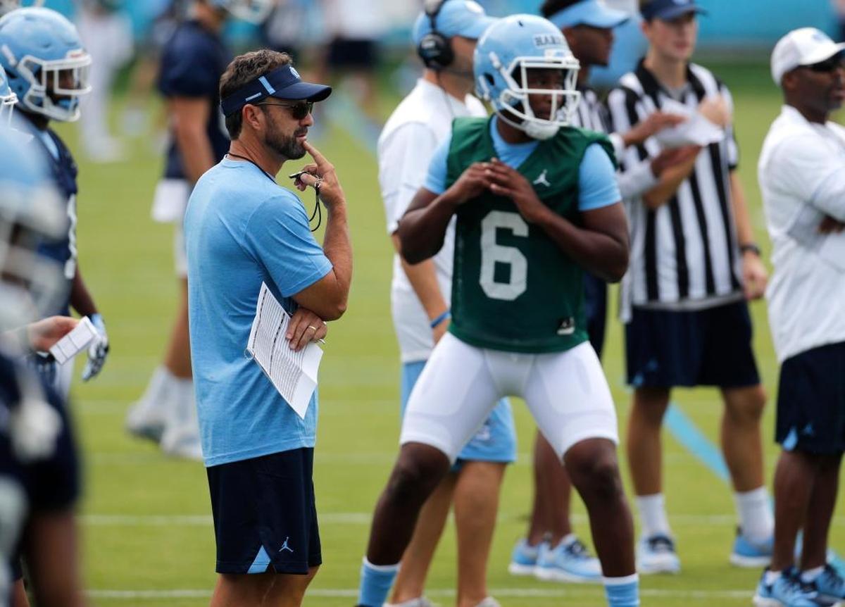 UNC coach Larry Fedora, left, watches quarterback Brandon Harris (6) during a drill on UNC’s first day of football practice.