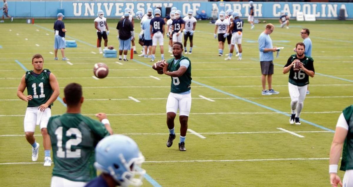 Quarterbacks Nathan Elliott (11), Brandon Harris (6) and Manny Miles (16) throw passes during a drill at UNC’s first football practice on Wednesday.