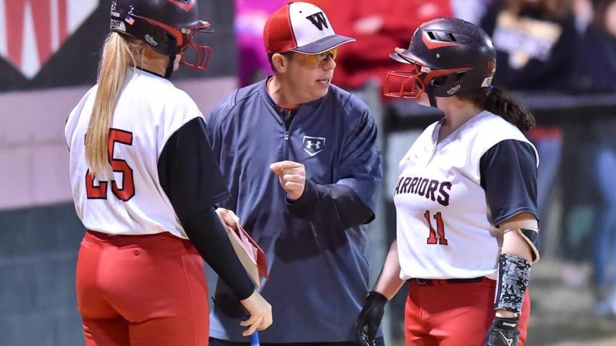 J.F. Webb head softball coach Leo Brunelli instructs Hailee Cutts (25) and Kaitlin Brunelli (11) during a time out. The South Granville Vikings took on the J.F. Webb Warriors in a non-conference softball game in Oxford, N.C. on March 8, 2017. South Granville wins 9-4.