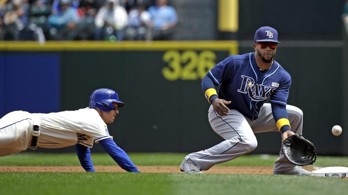 Seattle Mariners' Boog Powell, left, dives back to first base as Tampa Bay Rays' Rickie Weeks waits for the ball on a throw from home in the first inning of a game on June 4, 2017, in Seattle. Weeks has joined the Durham Bulls on an injury rehabilitation assignment.