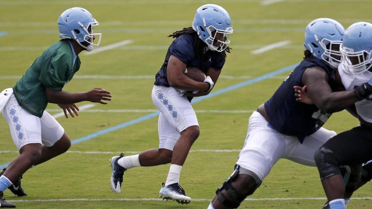 Running back Jordan Brown (2), center, runs through a drill after getting a handoff from QB Brandon Harris (6) as the UNC Tar Heels hold football practice at Kenan Stadium in Chapel Hill on August 2, 2017.